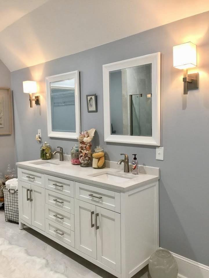 White double-sink cabinetry with framed mirrors and wall sconces